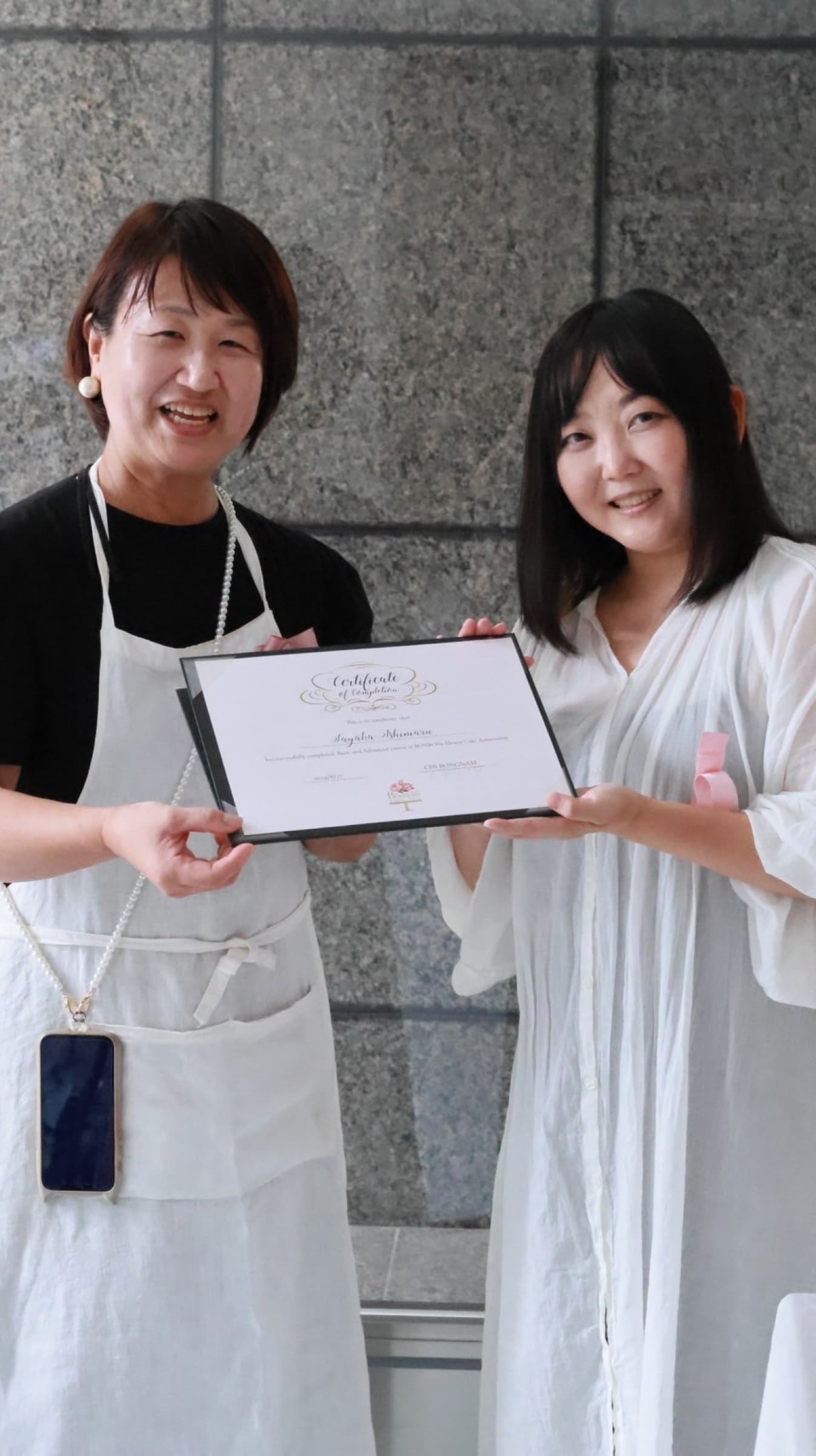 修了証を手にする受講生と講師